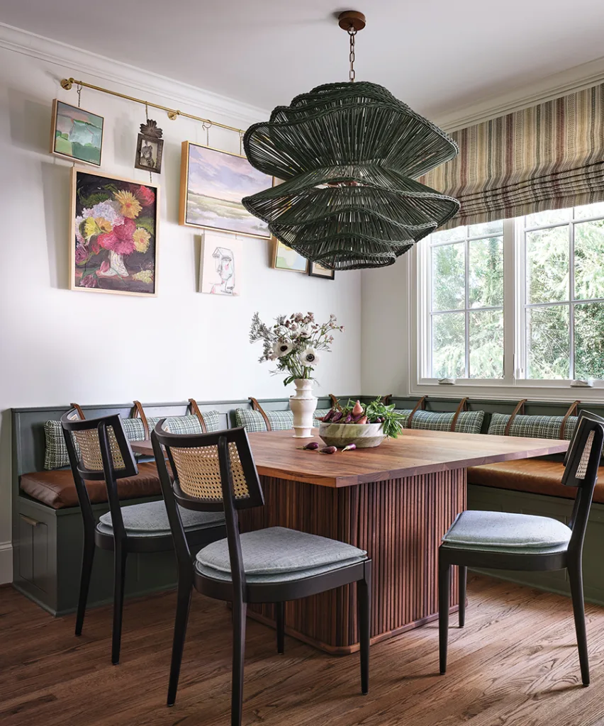 A larger dining area was a priority; an oversized pendant from Made Goods anchors the space, while an art bar creates visual interest above the banquette. The roman shade in a striped Zak & Fox fabric was made by Custom Window Treatments.
