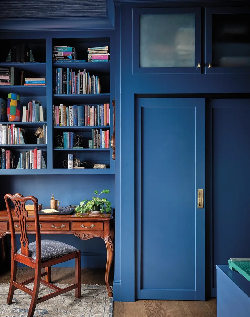 Writing desk and blue built in wall shelves and closet in the office.